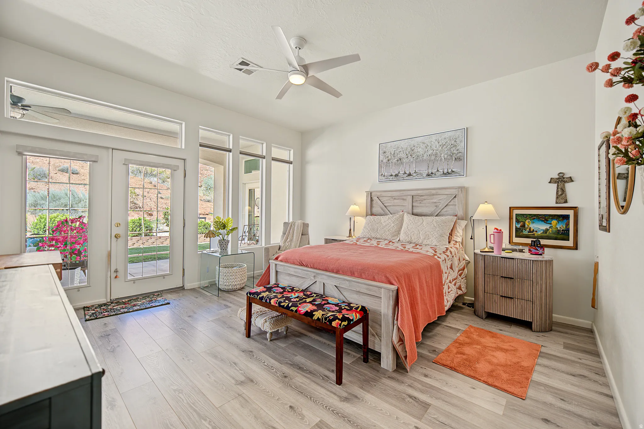 Wood-finish flooring, white walls, ceiling fan, and multiple windows with transoms
