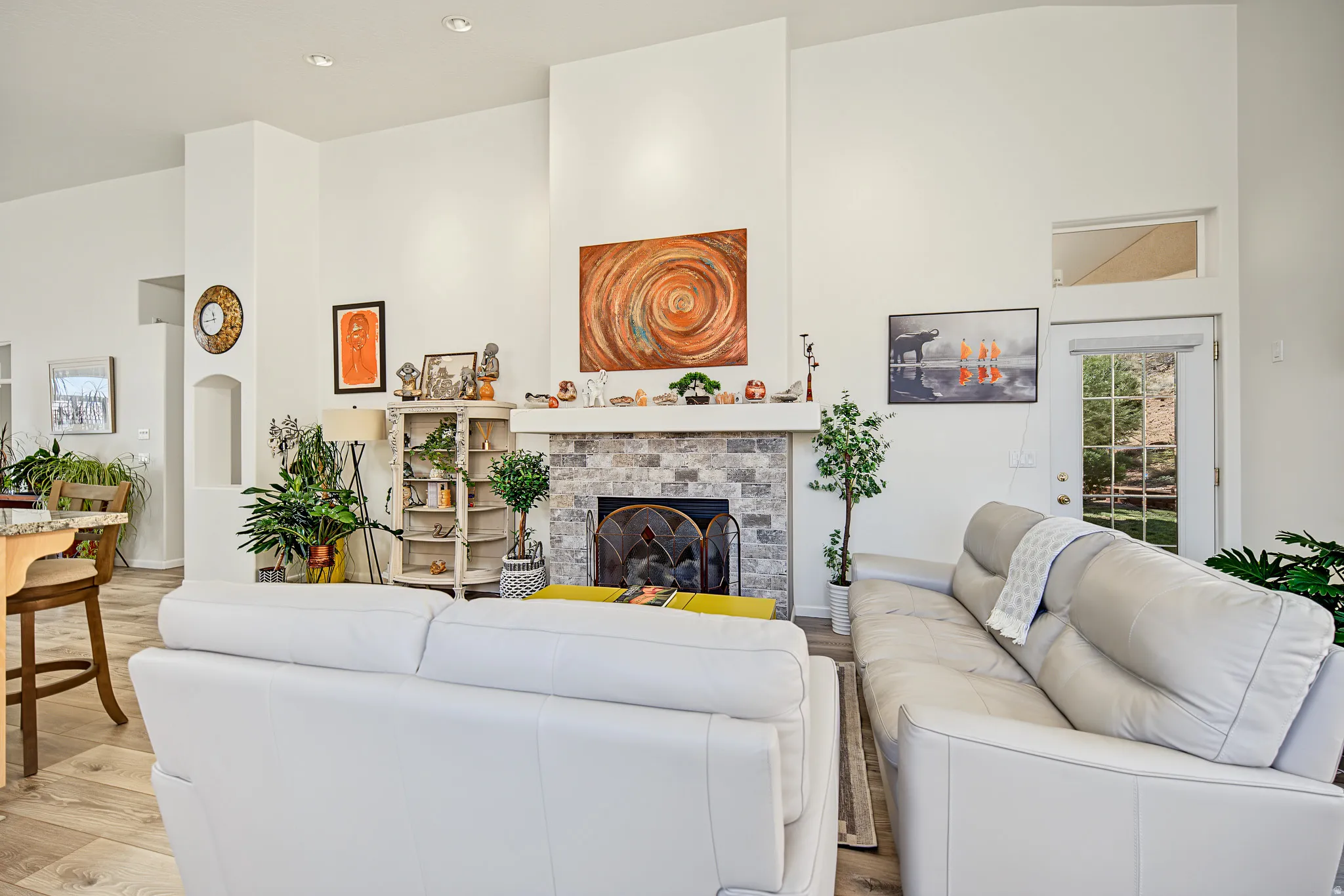 Living area featuring a floor-to-ceiling stone-faced fireplace, wood-finish flooring, recessed lighting, and a glass-paneled exterior door with transom window