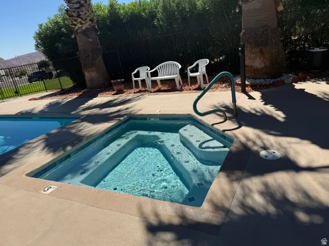 In-ground spa with integrated steps and a pool access handrail, set within a concrete deck