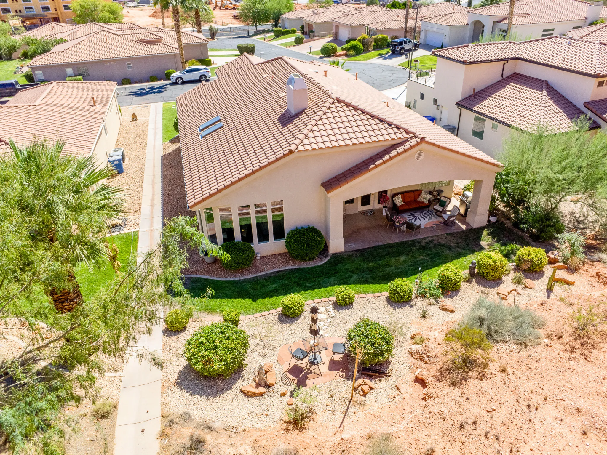 Mediterranean-style residence featuring a tile roof, covered patio, and a desert-landscaped backyard with natural rock elements