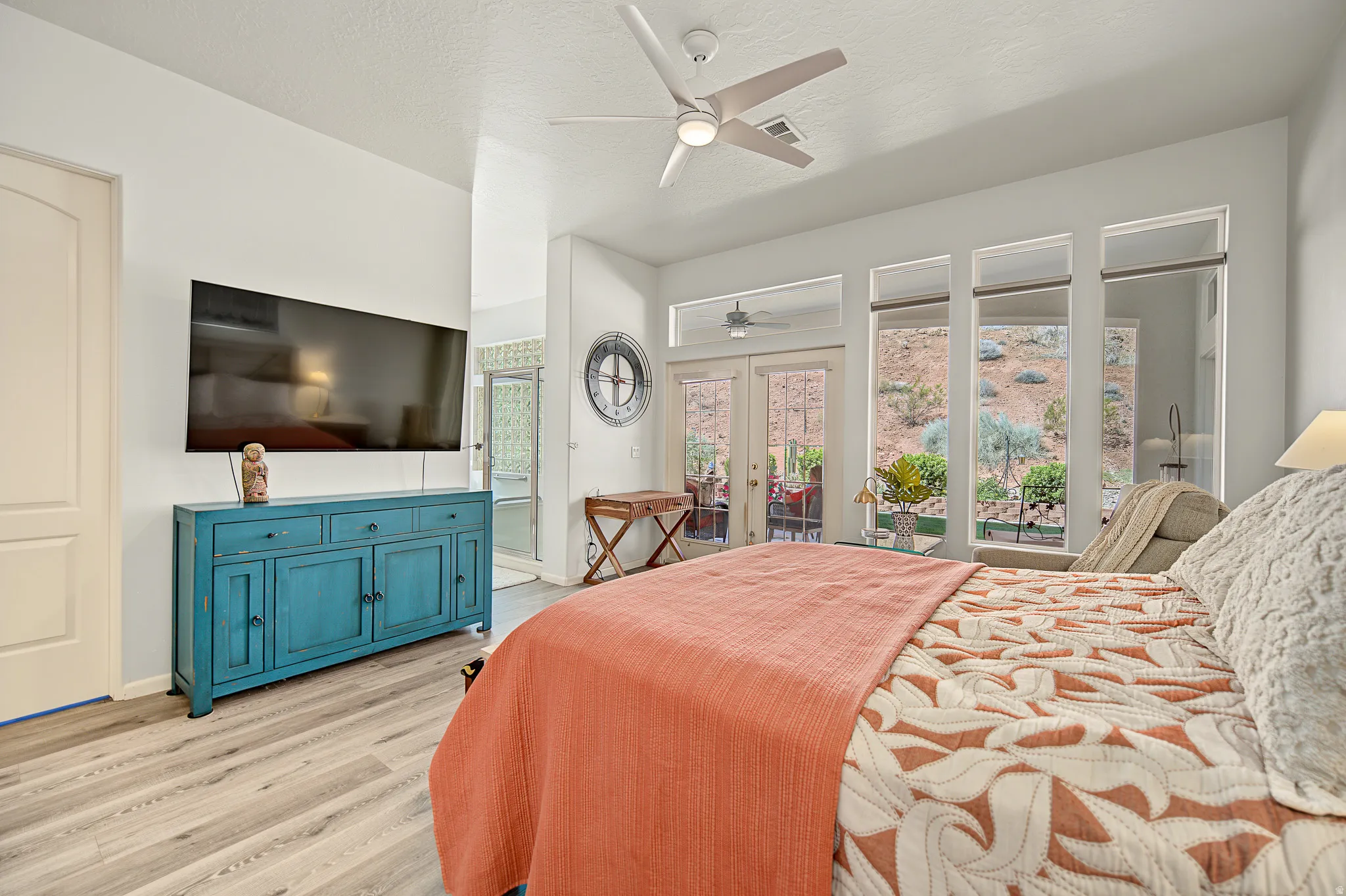 Wood-finish flooring, ceiling fan, and French doors with transom windows