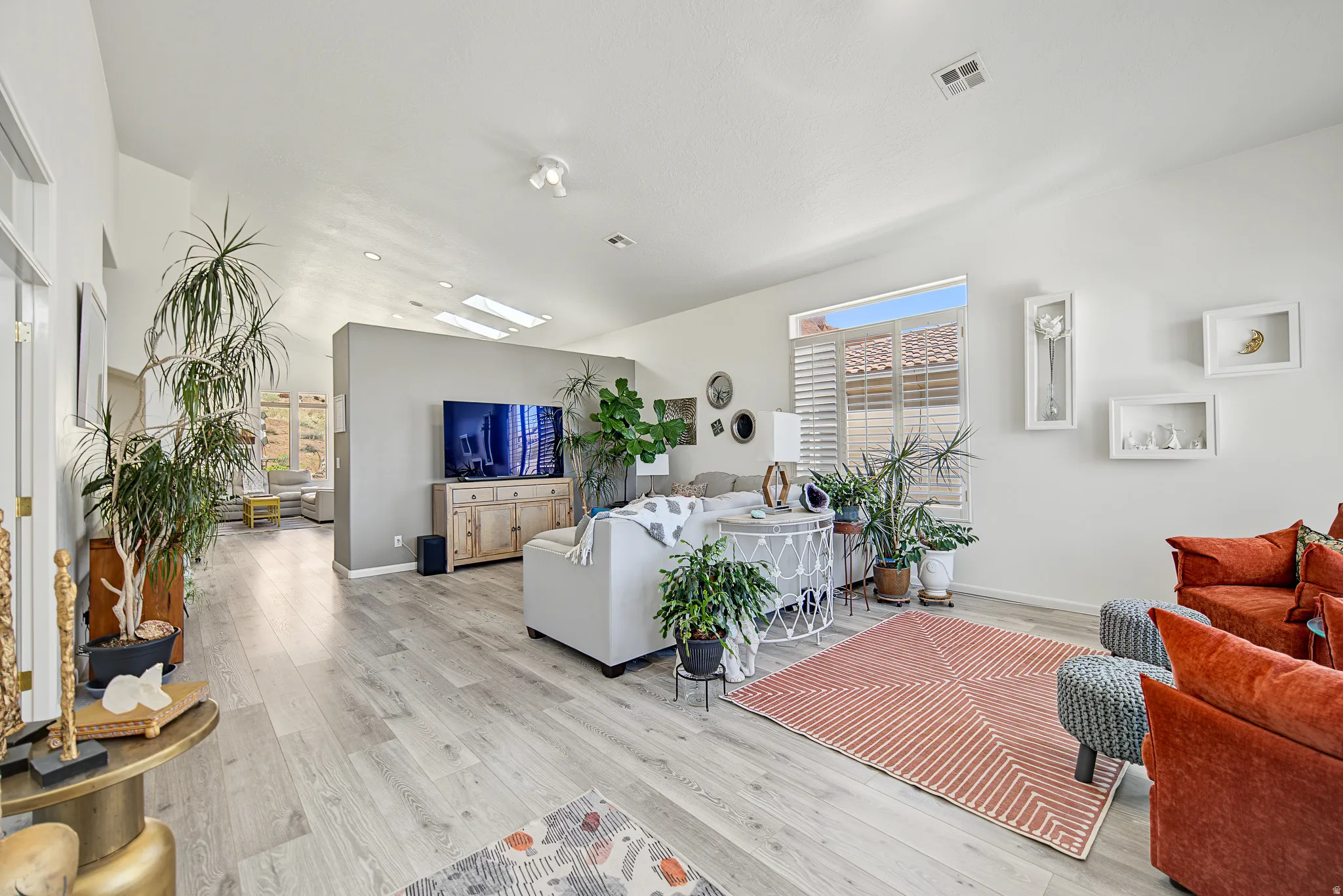 Vaulted ceilings with skylights, wood-finish flooring, interior plantation shutters, and recessed lighting