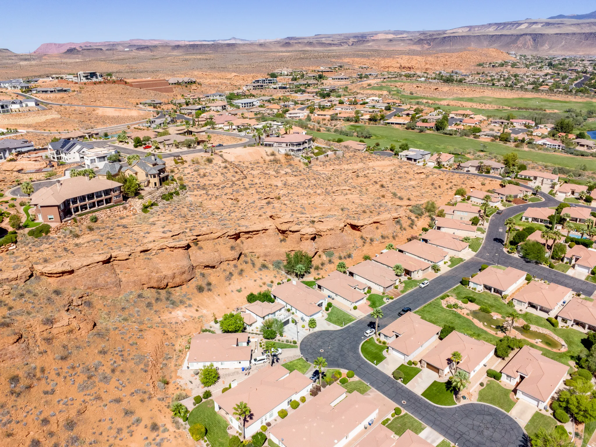 Expansive desert landscape with residential development, visible golf course, and distant mountains