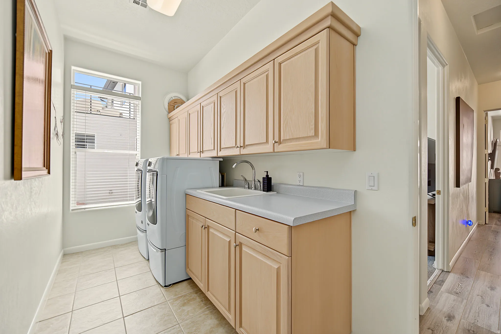 Laundry room featuring tile flooring, built-in cabinetry, an integrated sink, and a window with blinds