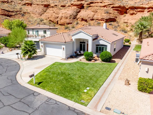 Stucco exterior with a terracotta tile roof, attached two-car garage, concrete driveway, and a verdant front lawn