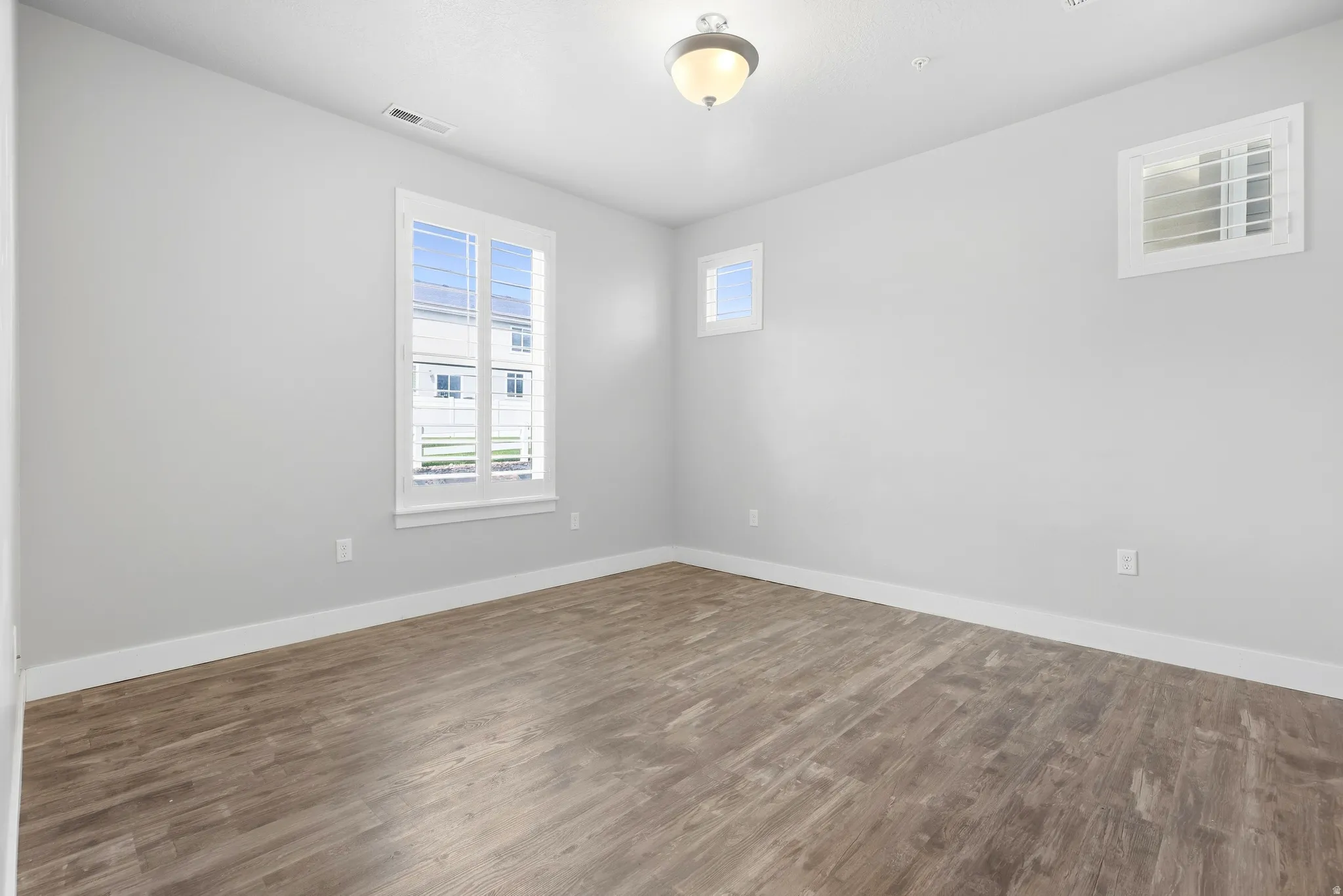 Wood-finish flooring, white trim, and two windows