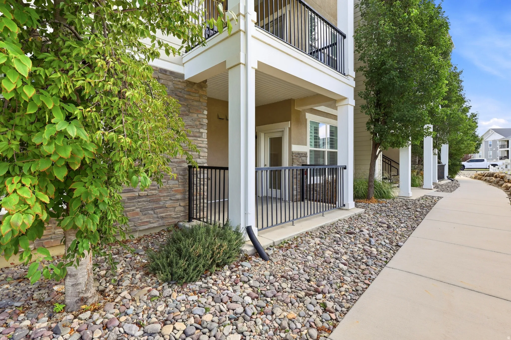 Building exterior featuring stone veneer, stucco siding, and a covered patio with black metal railings