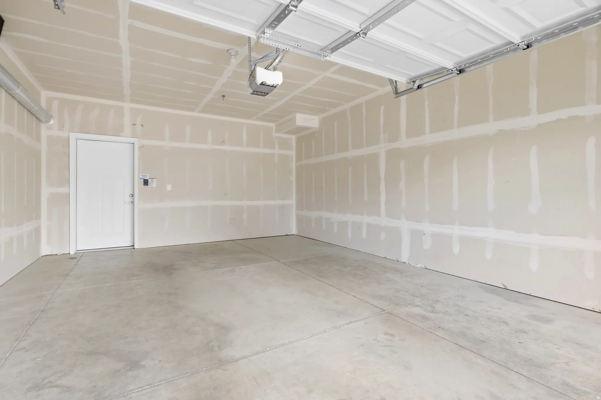 Concrete flooring, overhead garage door system, interior access door, drywall walls, overhead lighting fixture