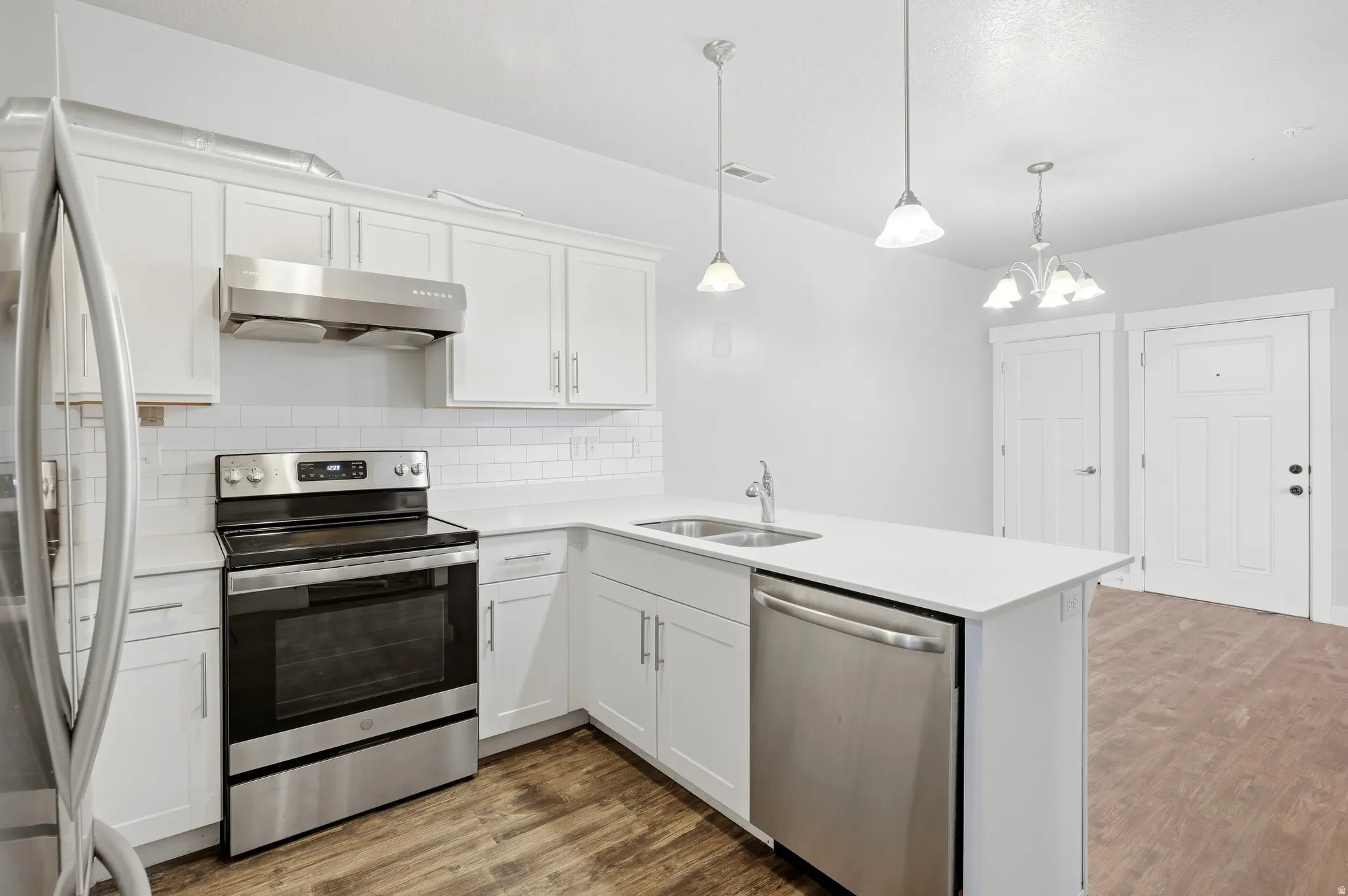 Kitchen featuring white shaker cabinetry, stainless steel appliances, white subway tile backsplash, white countertops, and wood-finish flooring