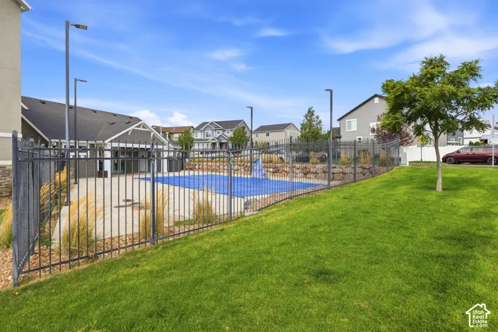 Fenced exterior leisure area with a covered pool and surrounding patio, featuring mature landscaping and a grassy expanse