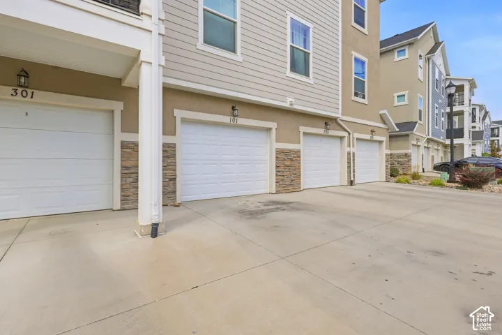 Attached garages with white panel doors, complemented by stone facade accents and tan stucco