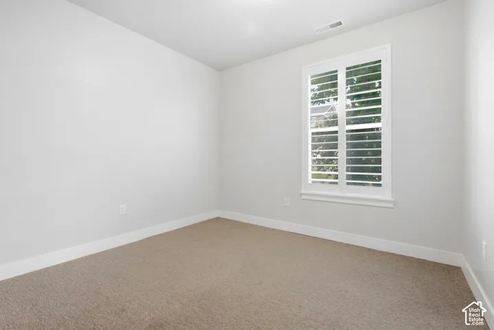 Recessed window with white plantation shutters, carpeted flooring, and light-colored wall finishes