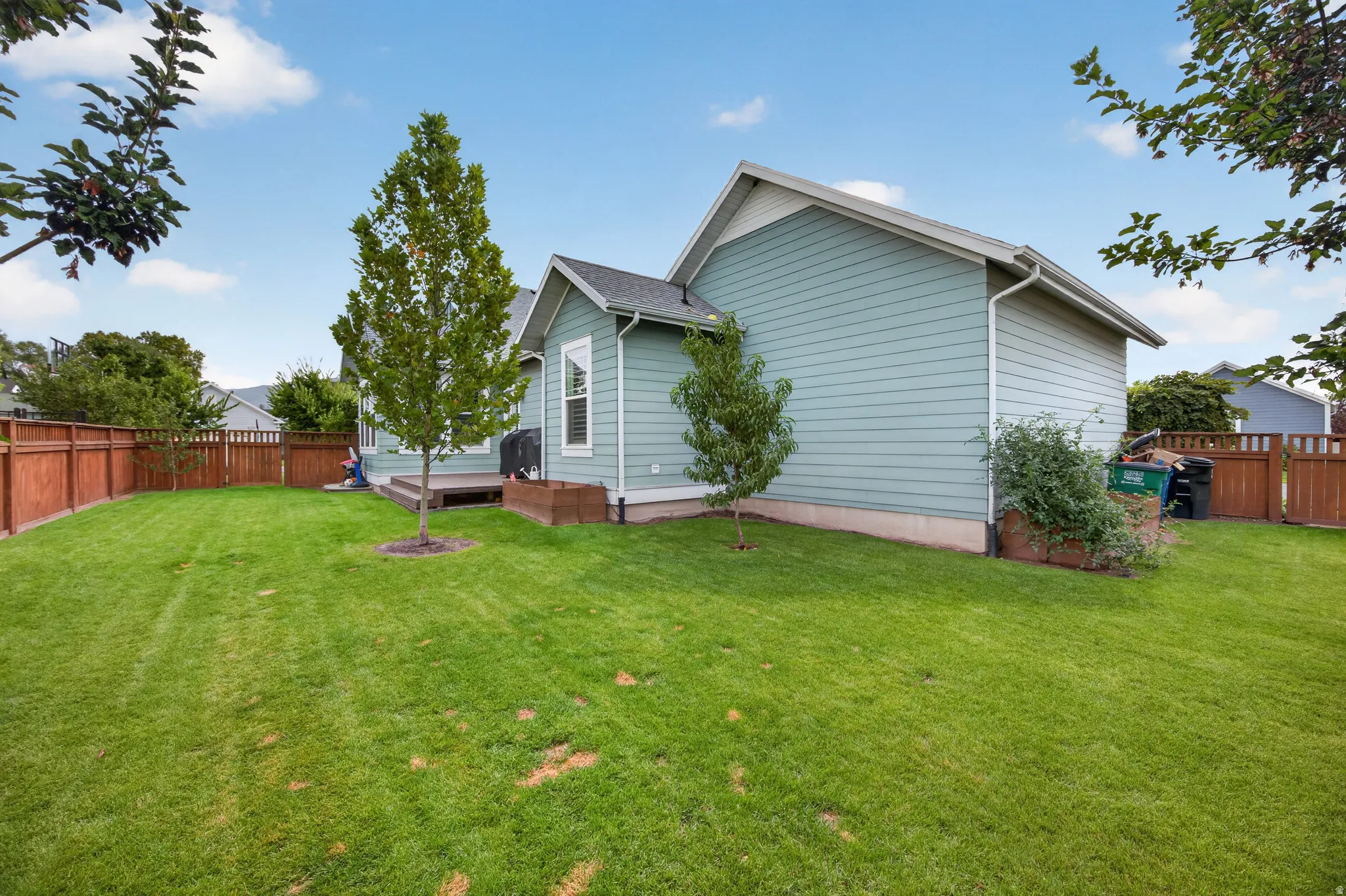 Expansive green lawn with mature trees and a wood-decked patio