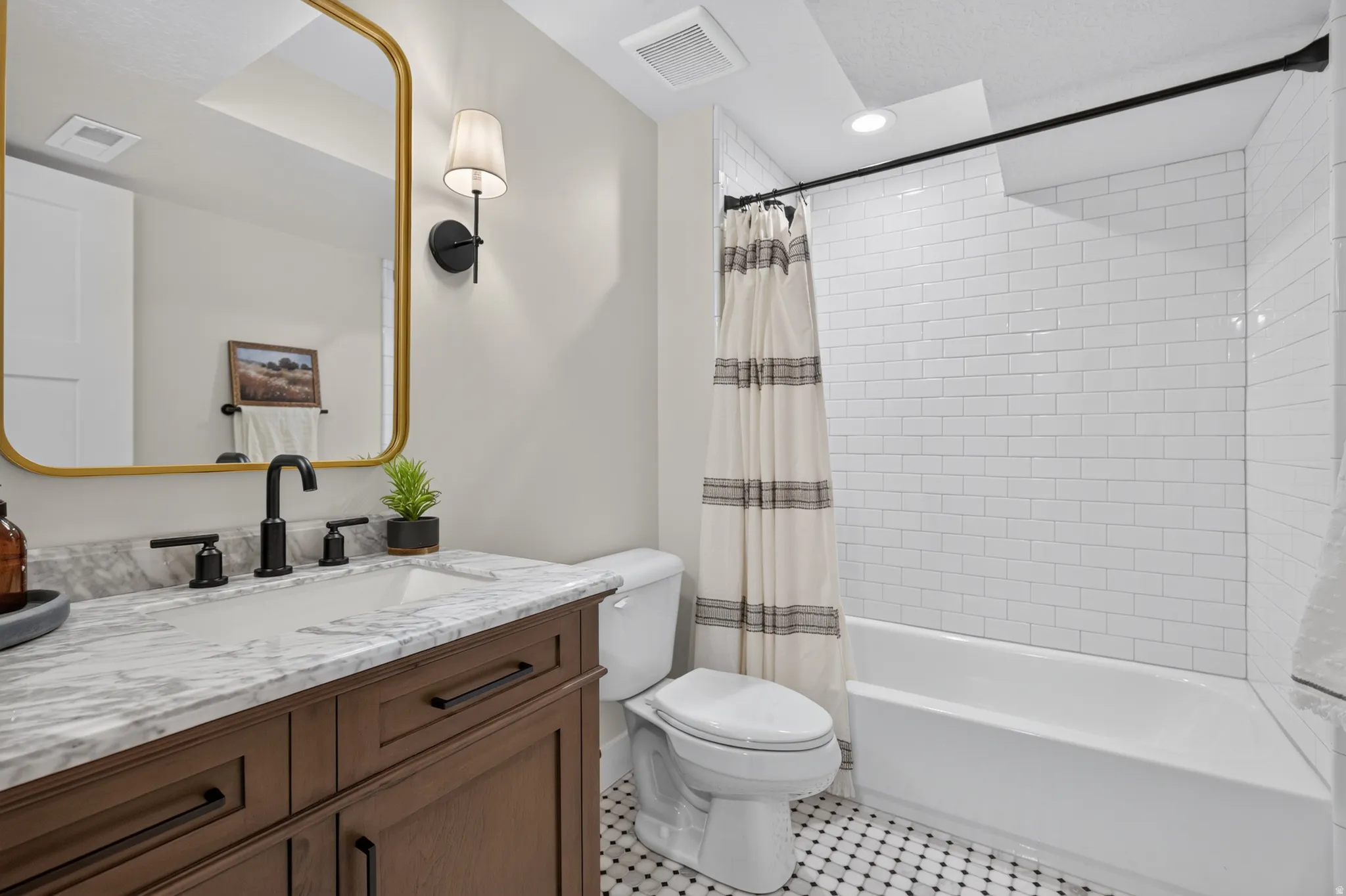 Bathroom featuring a wood-finish vanity with a stone countertop, an undermount sink, and matte black fixtures