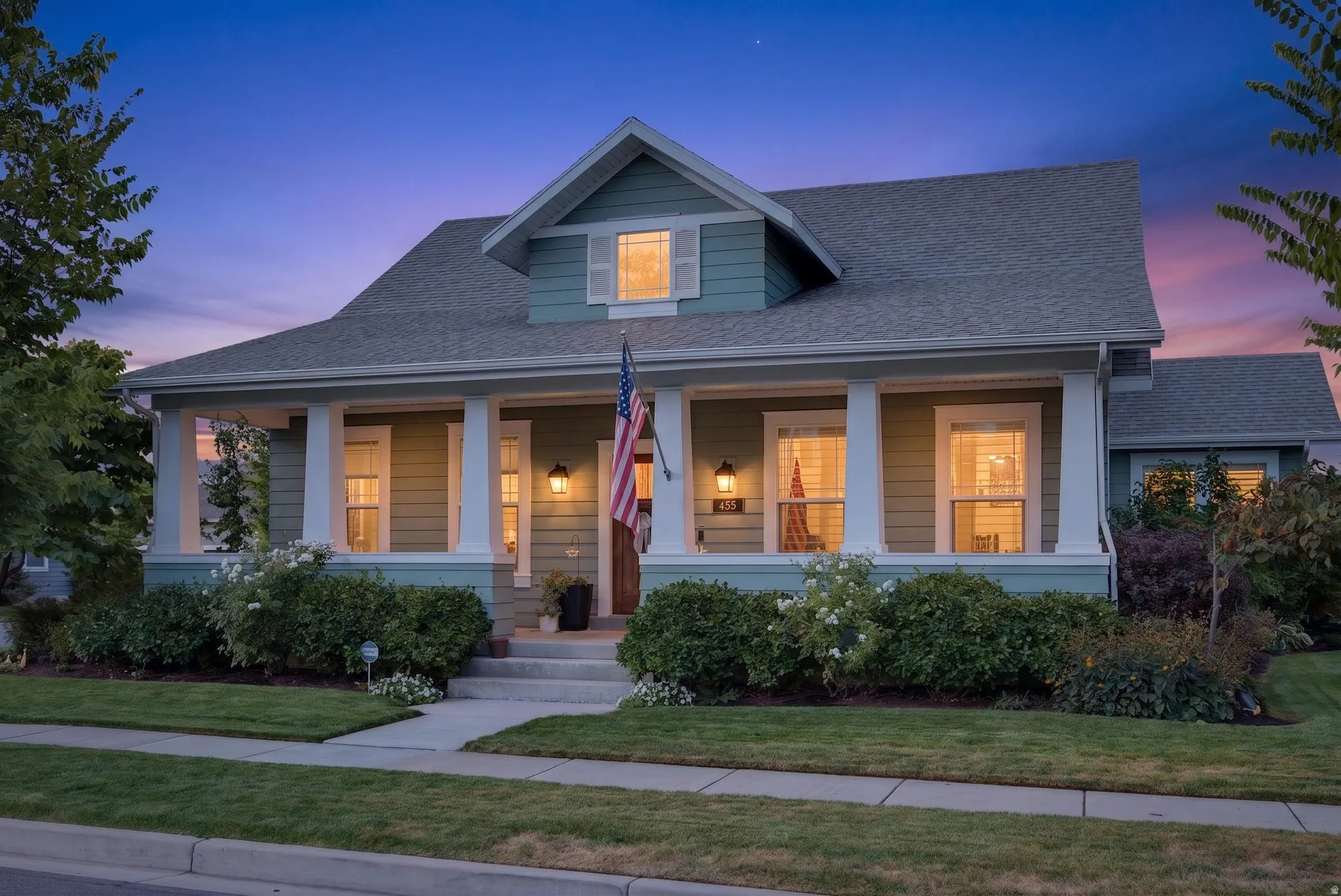 Craftsman-style home featuring a covered front porch with substantial columns, a pitched roofline, horizontal siding, and established landscaping