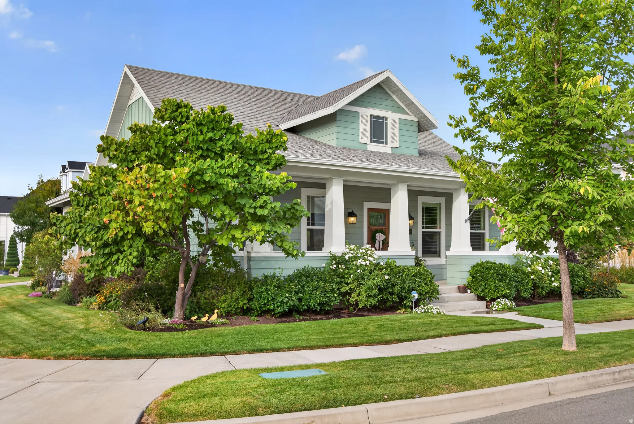 Craftsman-style exterior with a covered front porch, dormer window, and mature landscaping