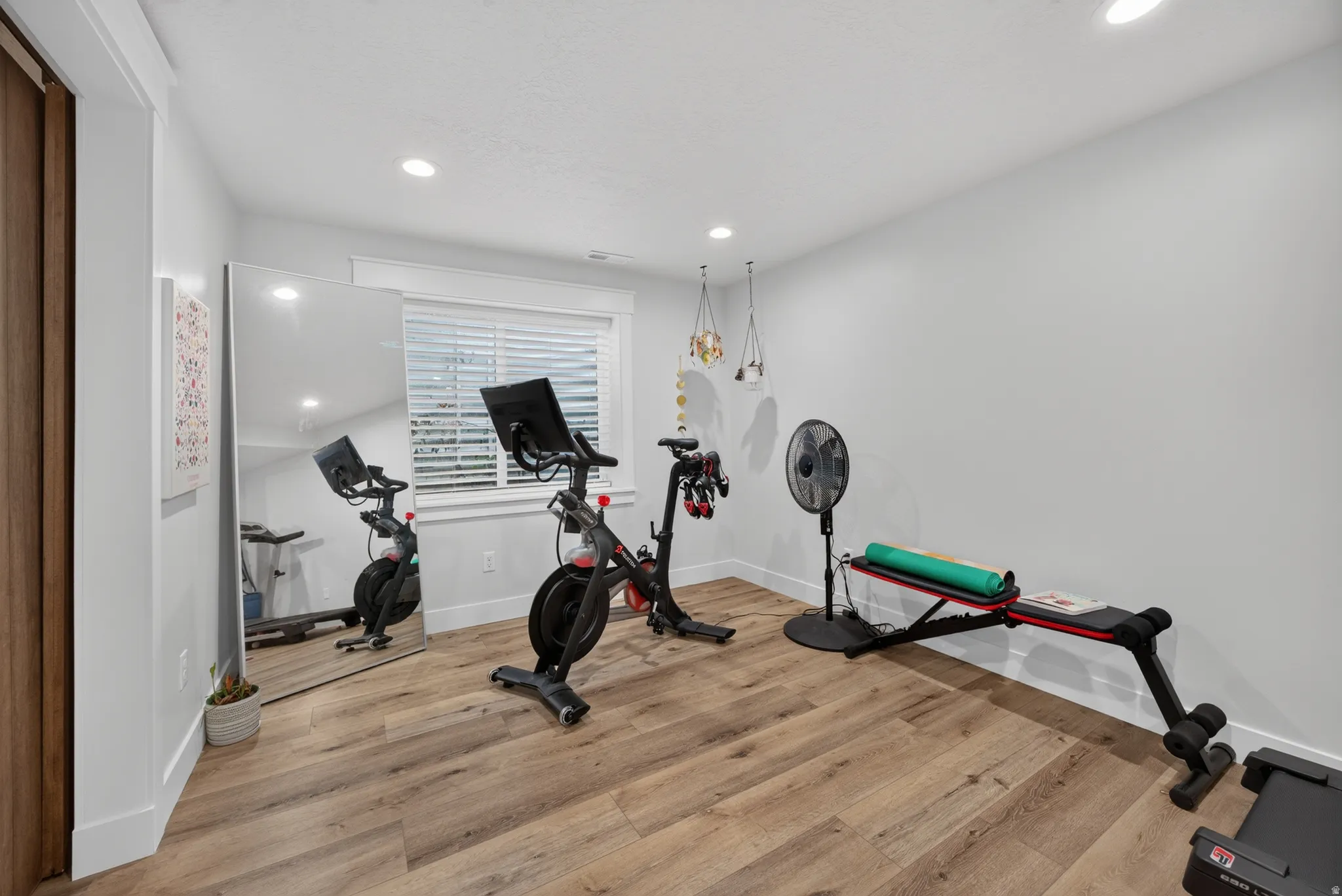 Wood-finish flooring, recessed lighting, a window with blinds, and white trim