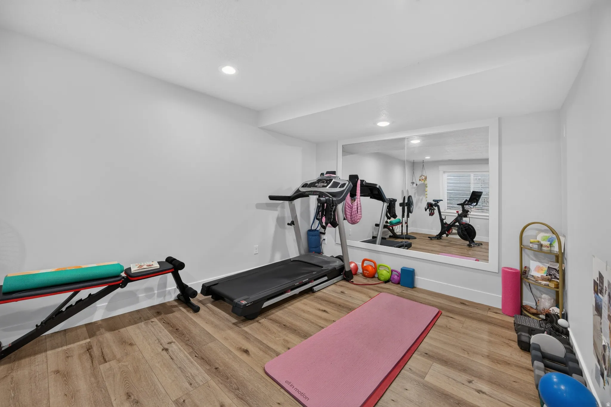 Room featuring wood-finish flooring, recessed lighting, and a full-wall mirror