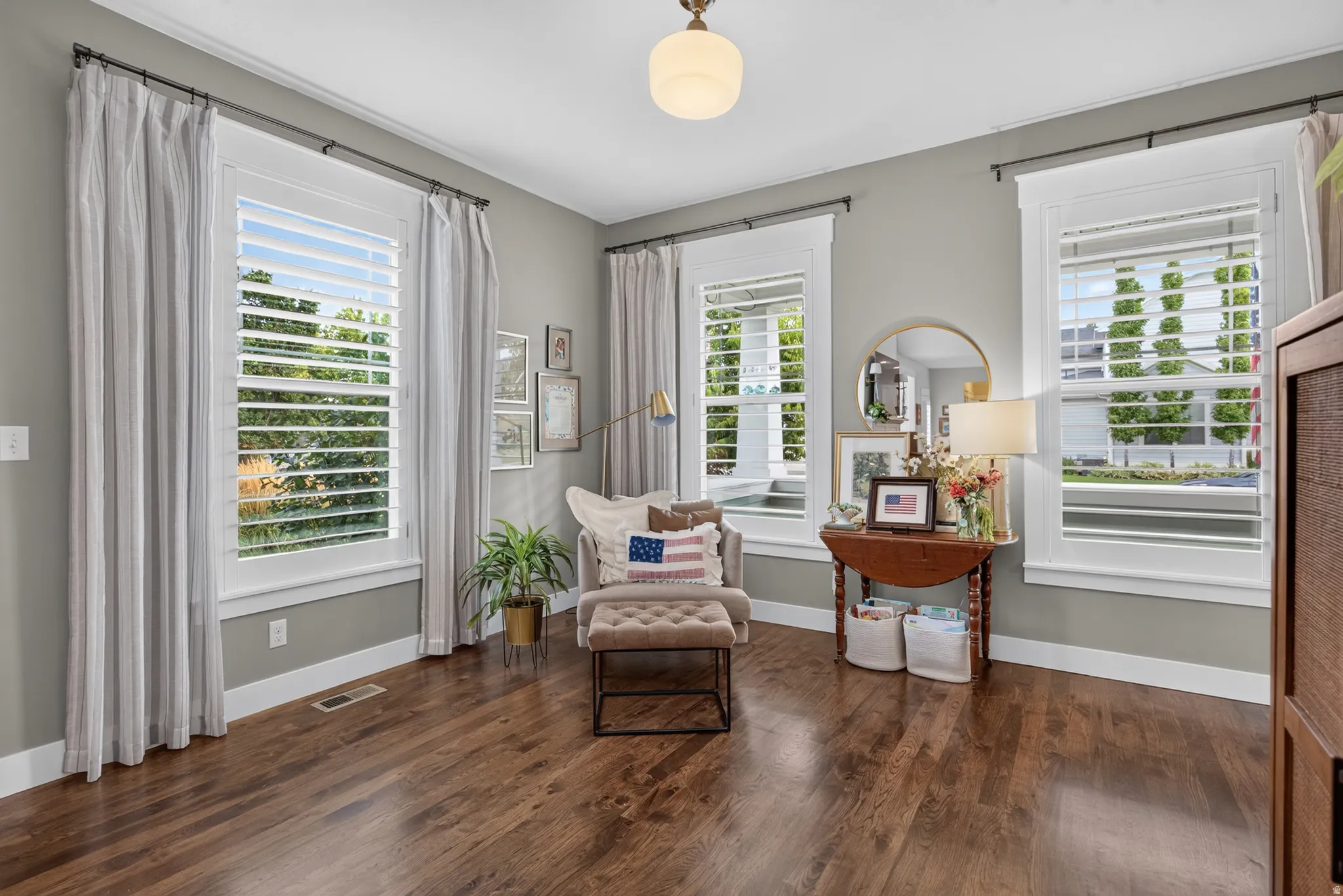 Wood-finish flooring, white window shutters, crown molding, and a built-in wooden cabinet