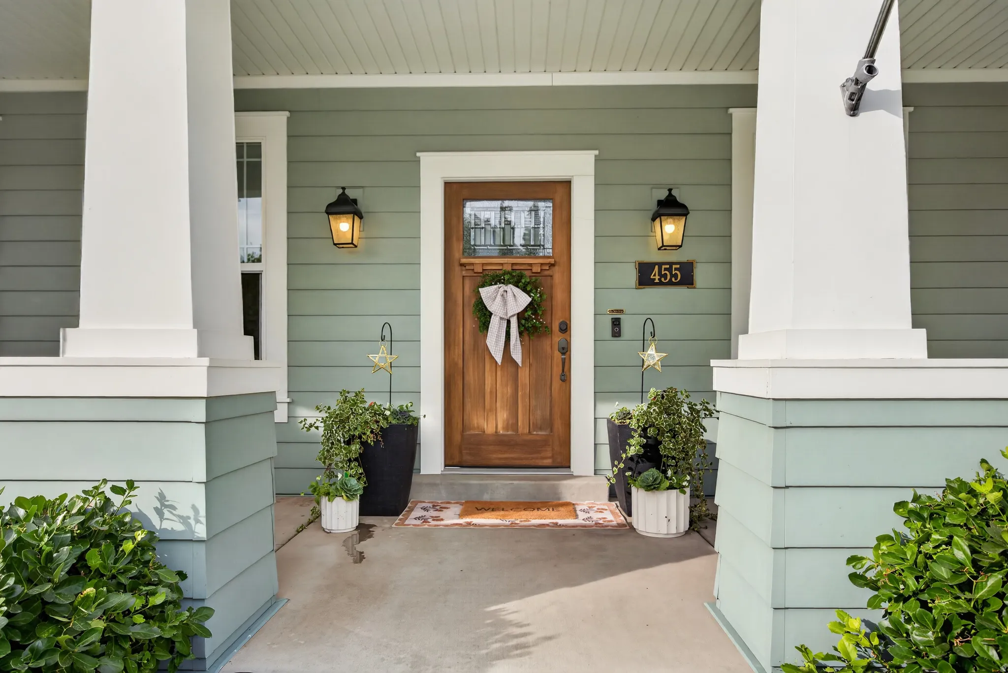 Entry with warm wood-finish door, side light window, and twin exterior wall lanterns