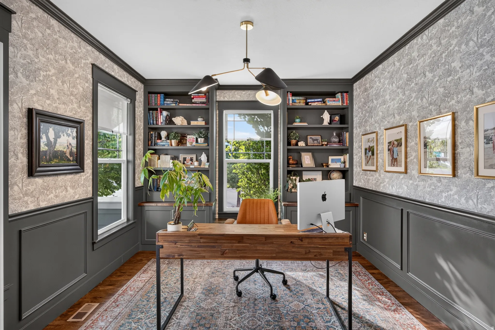 Built-in shelving, wood-finish flooring, detailed wainscoting, and a modern chandelier