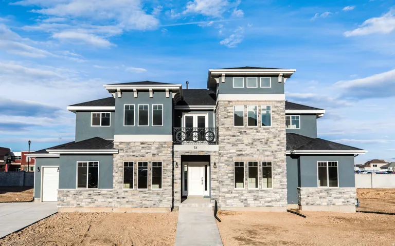 Contemporary exterior with multiple roof lines, stone and stucco facade, a prominent entry tower, an ornamental balcony, and a two-car garage