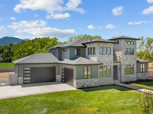 Contemporary stone and siding exterior with multiple rooflines, a multi-car garage, and a concrete driveway