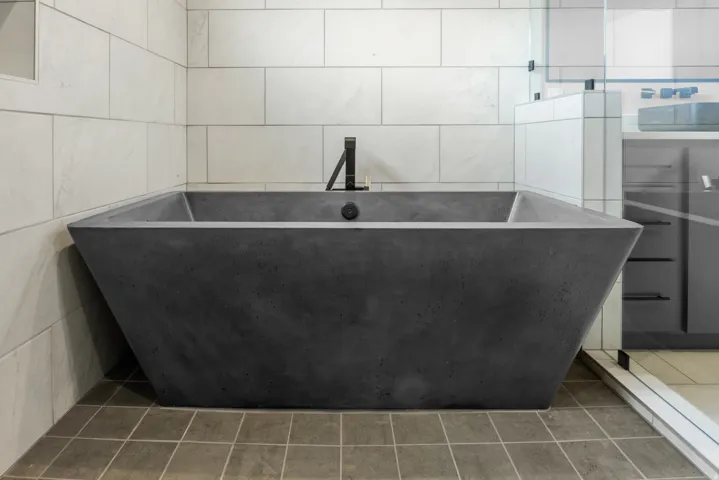 Freestanding soaking tub with matte black fixtures, set against light-toned subway tile walls and square floor tiles