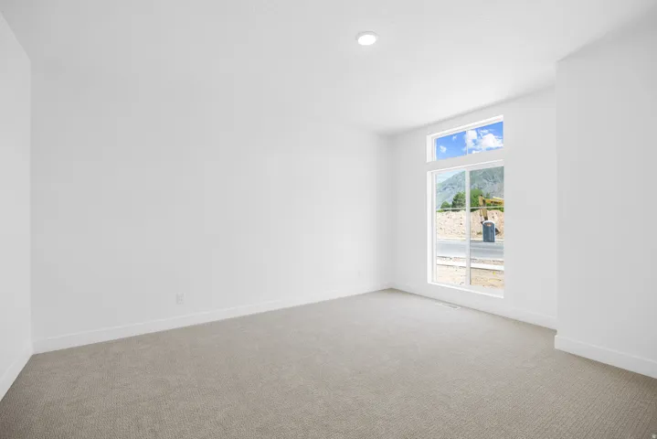 Recessed ceiling lighting, large window with transom, neutral carpet flooring, white walls, and white trim