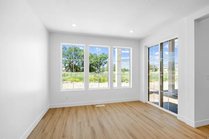 Wood-finish flooring with white walls, recessed ceiling lighting, three paneled windows, and a sliding glass door