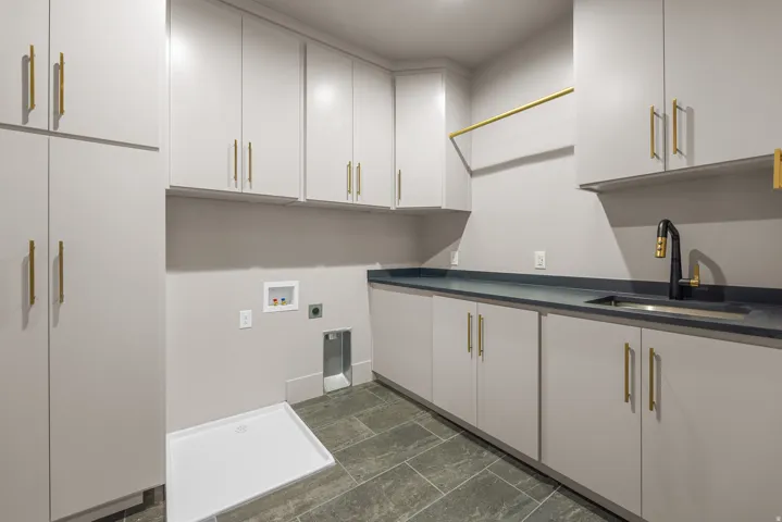 Full-height cabinetry, extensive upper and lower storage, dark countertop, integrated sink with black faucet, and tile flooring