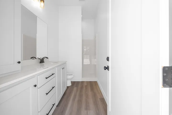 White vanity with a light-toned countertop, undermount sink, and black fixtures