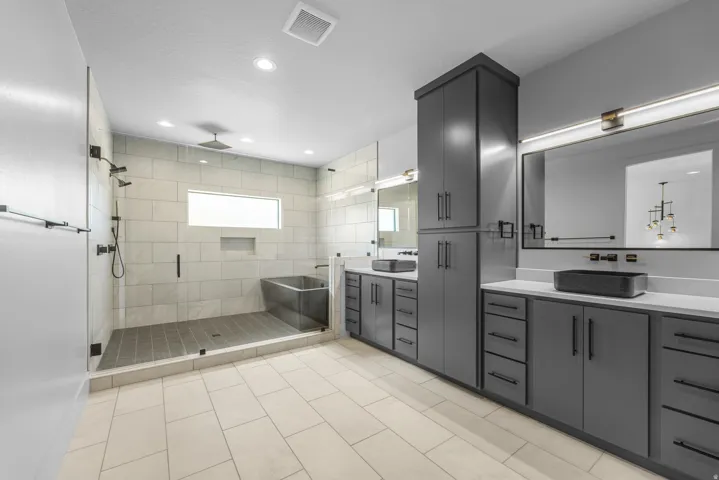 Spacious bathroom featuring a dual vanity, recessed lighting, matte black fixtures, a walk-in shower with a rain shower head, and a soaking tub