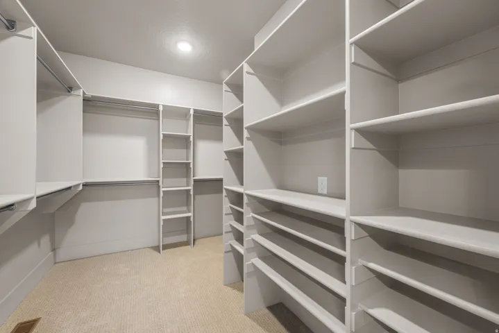 Walk-in closet featuring extensive built-in shelving, multiple hanging rods, and recessed lighting