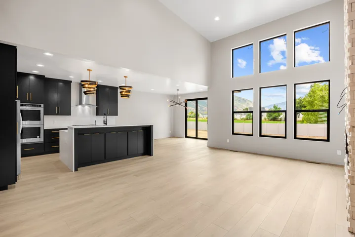 Vaulted ceilings, a full suite of stainless steel appliances, a kitchen island with storage, wood-finish flooring, and large windows