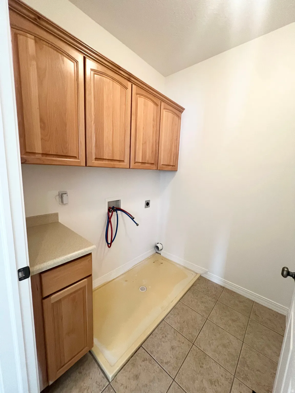 Tile flooring with a floor drain, wood-finish cabinetry, and solid surface countertop