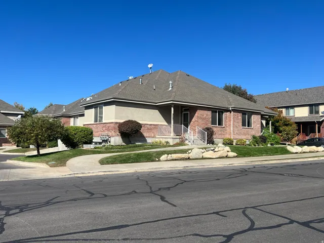 Brick and stucco exterior with multiple windows, covered porch with white railings, and a concrete pathway