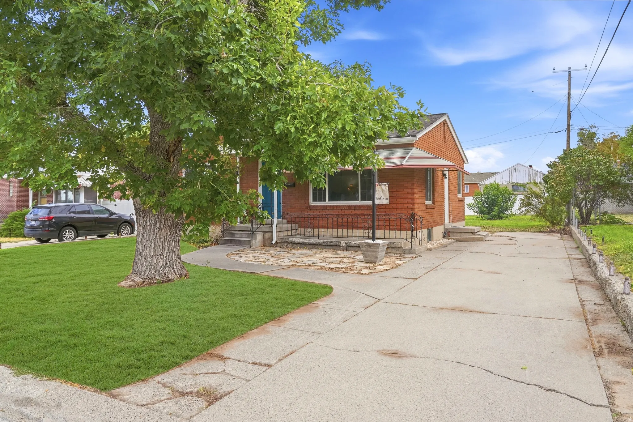 Red brick exterior with white trim, a covered entry, and a concrete driveway
