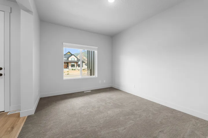 Neutral wall color, recessed lighting, and a single window with blinds