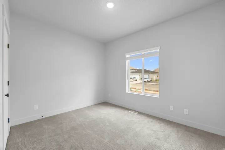 Neutral color palette, recessed lighting, carpet flooring, window with roller shades, white trim