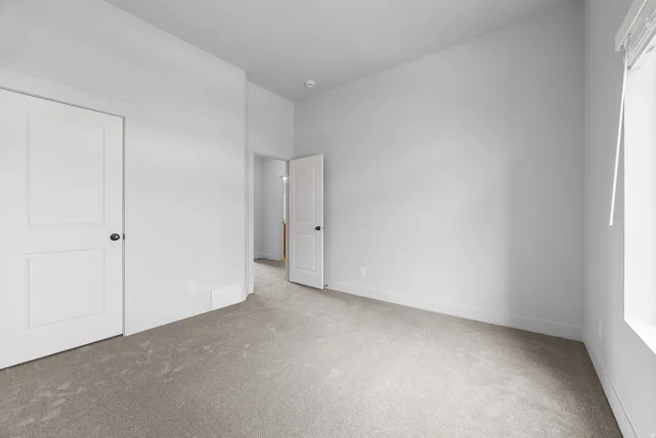 Neutral-toned carpeting, white interior doors with black hardware, and a window with blinds