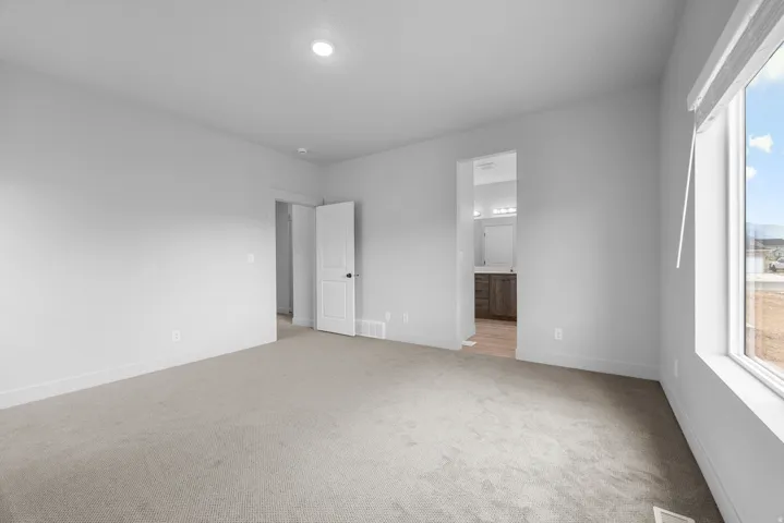 Carpeted flooring, recessed ceiling light, white trim, and a window with a roller blind