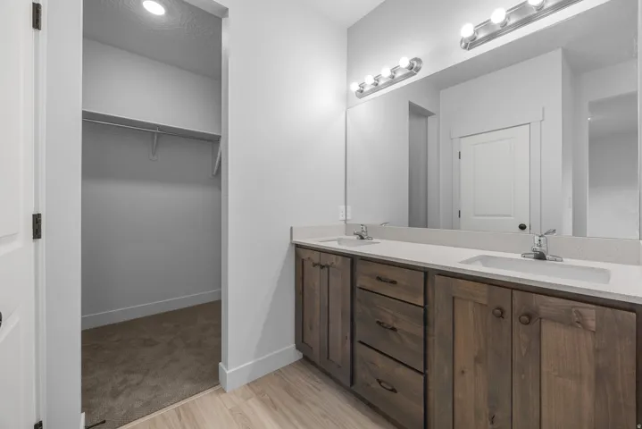 Dual vanity with wood-finish cabinetry, integrated sinks, and polished chrome fixtures