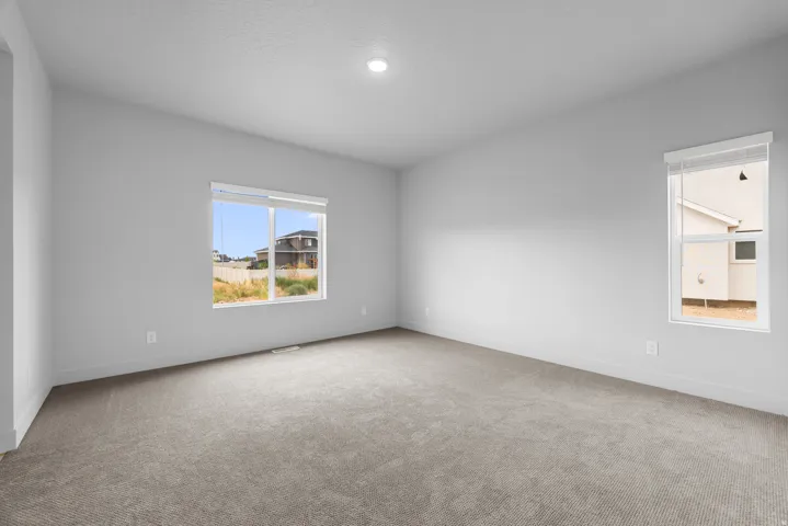 Spacious room featuring neutral carpeting, light-toned walls, and recessed lighting