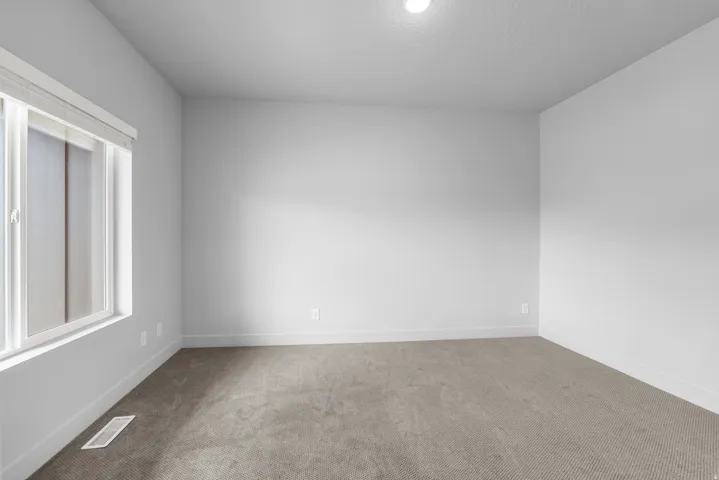 Recessed ceiling lighting illuminates light gray walls and plush gray carpeting