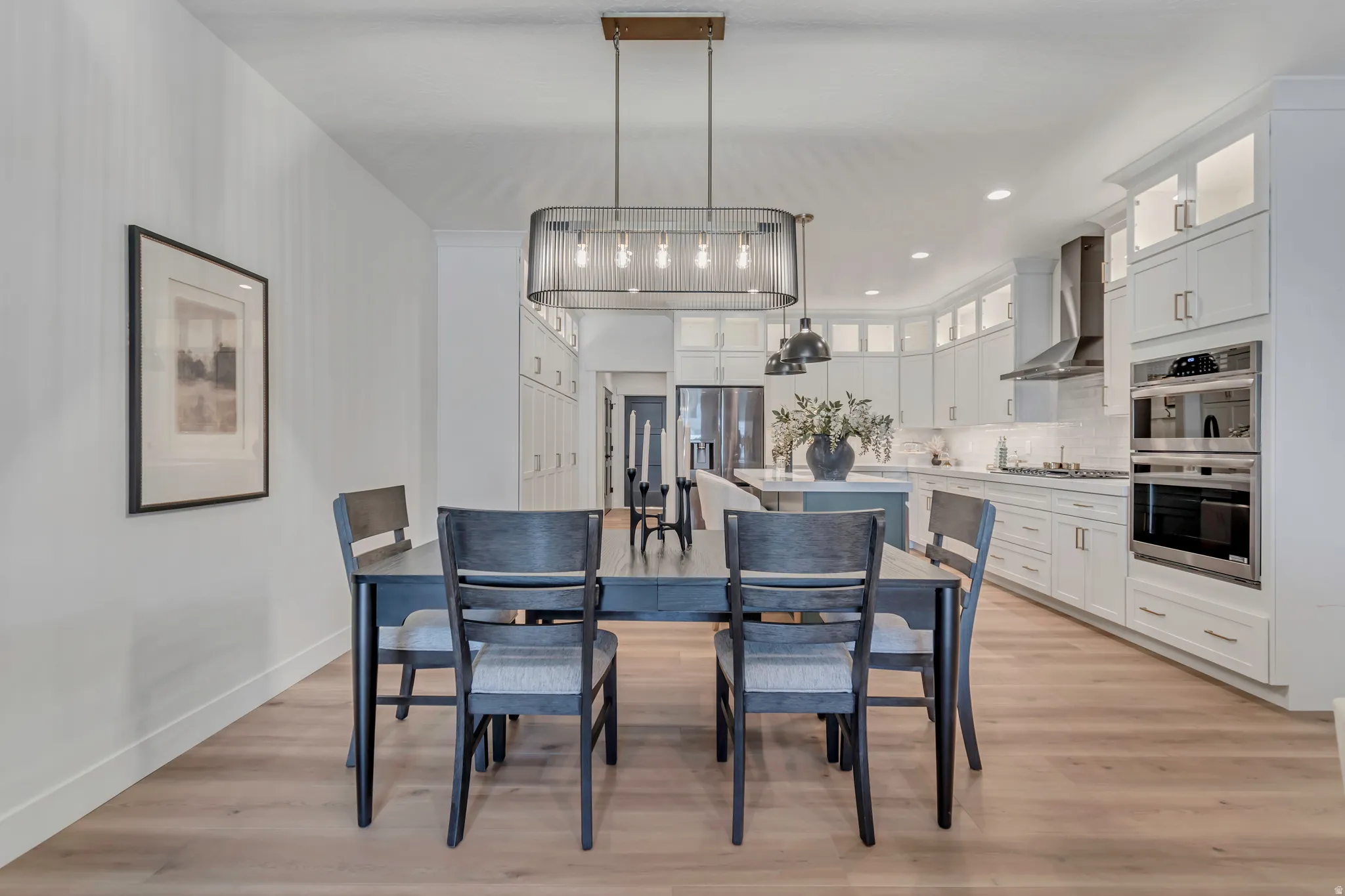 Wood-finish flooring throughout, kitchen with white cabinetry, stainless steel double oven, and stainless steel range hood