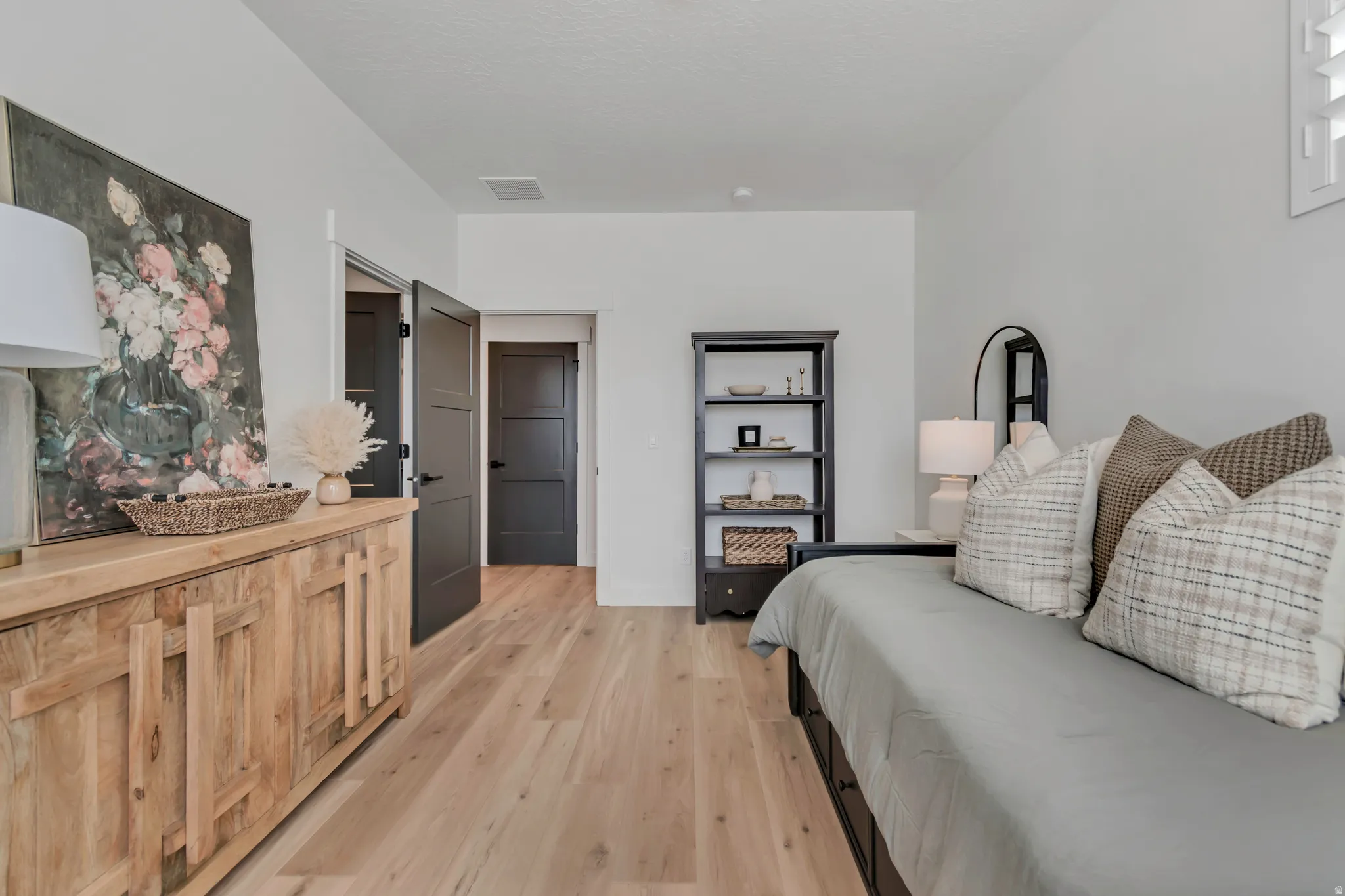 Wood-finish flooring throughout, white walls, and dark panel doors