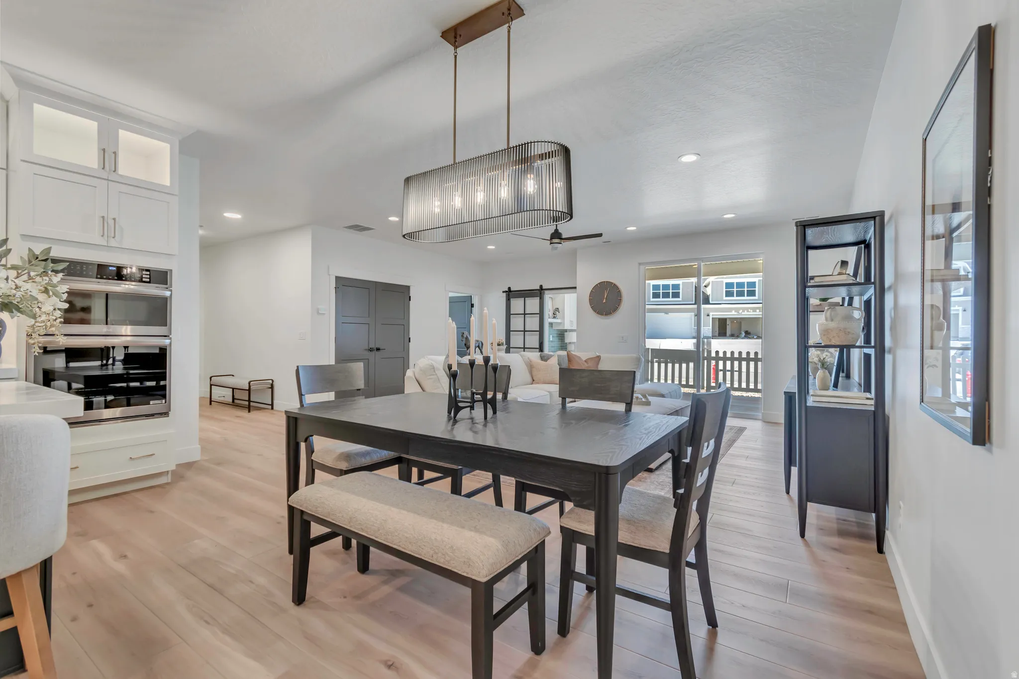 Open-concept living area featuring light wood-finish flooring, a contemporary linear pendant light, and recessed lighting
