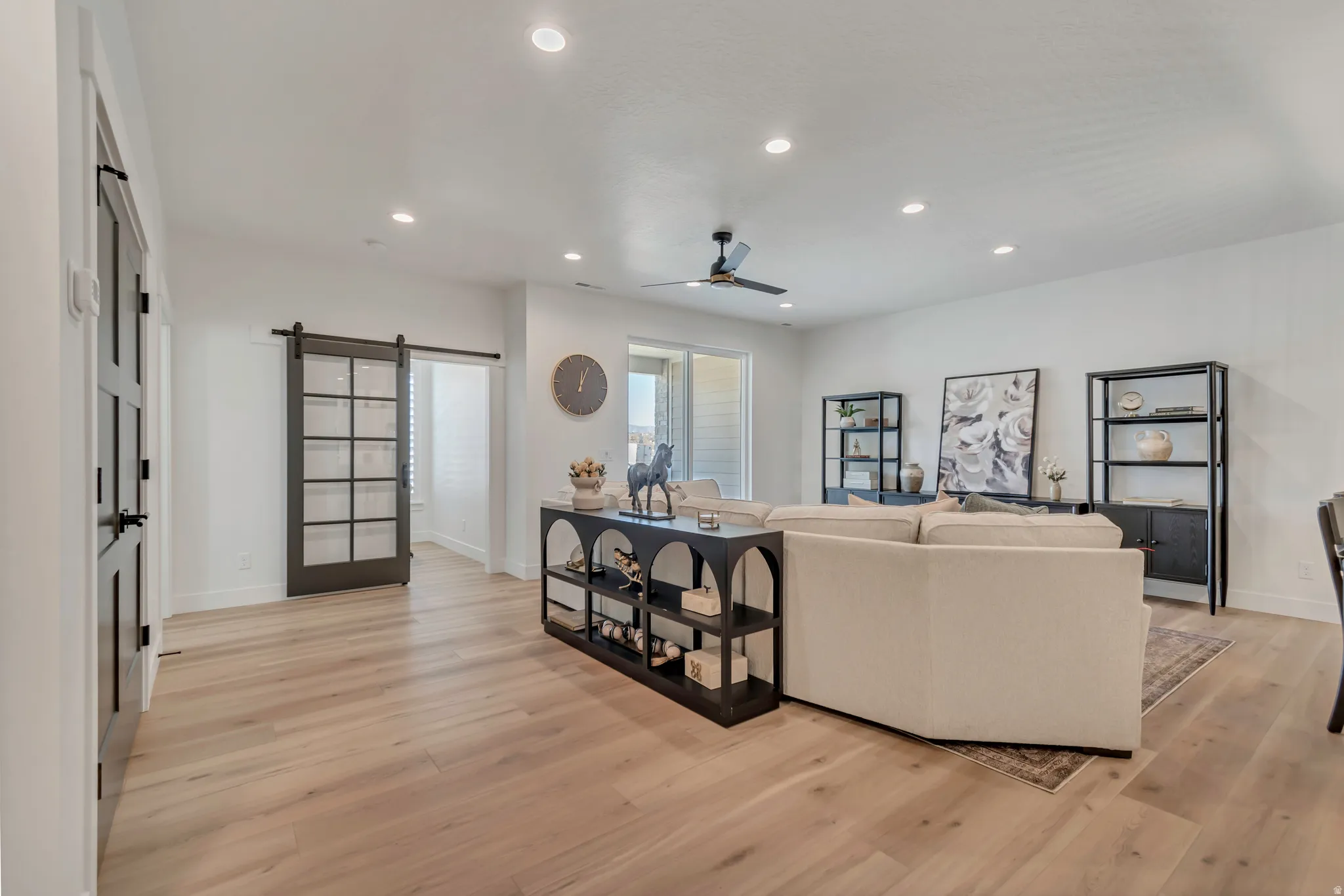 Expansive living area with wood-finish flooring, recessed lighting, and a ceiling fan