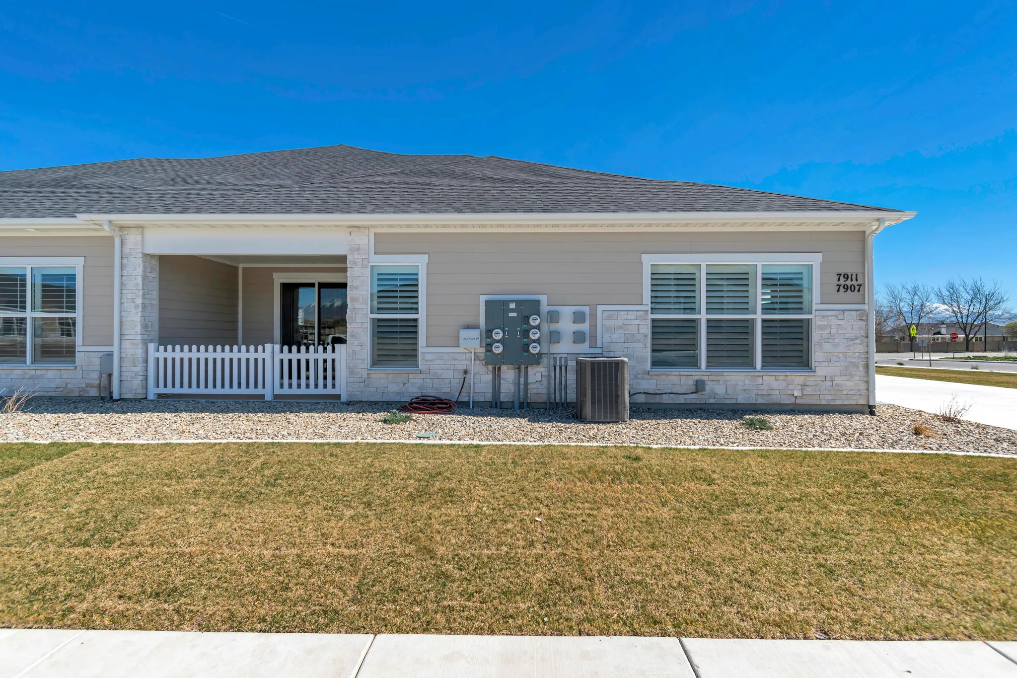 Exterior featuring light-toned siding, stone accents, and multiple windows with horizontal blinds